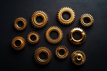The gold gears isolated in black background. Concept of precision and engineering. - obrazy, fototapety, plakaty