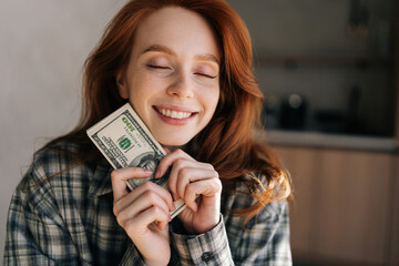 Closeup portrait of happy female freelancer holding in hands wad of dollars that she earned while...