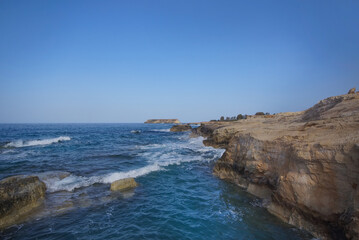  Waves Crashing on Rocky Beach. The white foamy spray contrasts with the dark tones of the rocks, illustrating the harsh beauty of the coastal landscape
