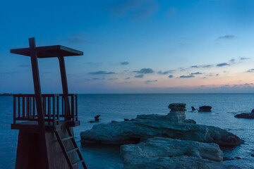 Serene Twilight Over a Coastal Lifeguard Tower at Dusk. In the foreground, a solitary lifeguard...