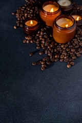 Soy scented candle in a jar. Coffee beans, anise, cinnamon spices. The candles are burning. Dark copy space background