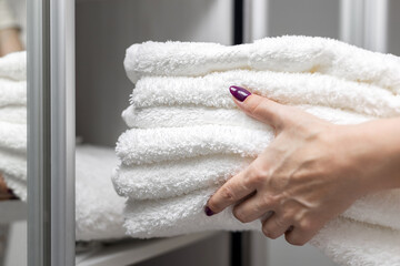 woman putting white towels in the closet.