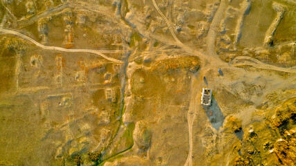 Traces of dirt roads and ruined houses mark the site of a former village, now submerged beneath the reservoir formed by a breached dam, with only the surviving church of St. Ivan Rilski, Bulgaria