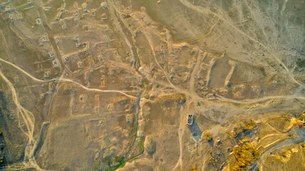 Traces of dirt roads and ruined houses mark the site of a former village, now submerged beneath the reservoir formed by a breached dam, with only the surviving church of St. Ivan Rilski, Bulgaria