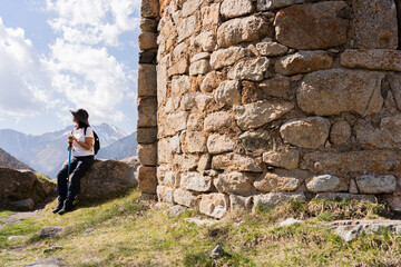 Woman resting while contemplating from the top of the mountain after a long day of trekking next to...