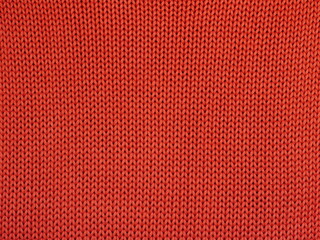 Closeup of orange knitted fabric with large stitches. Textured unicolor background.