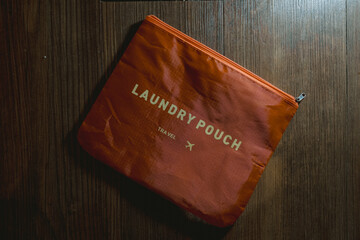 An orange laundry pouch on the wooden floor for travel with flay lay angle