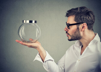 Man holding and looking at an empty glass jar 