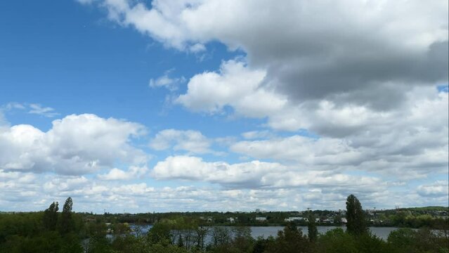 White clouds passing through a blue sky. Time lapse of cumulonimbus clouds over a lake.