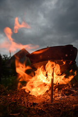 A cast iron cauldron stands under a blazing fire.