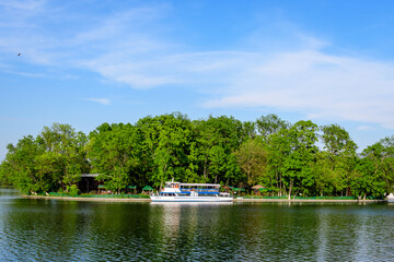 Landscape with white boats on Herastrau lake and large green trees in King Michael I Park (former...