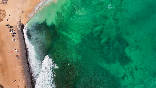 Following a breaking wave from above at Ponta Preta, Sal, Cape Verde. Surfers can be seen

