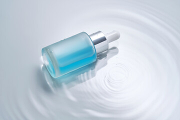 Bottles of cosmetics with a dropper in water on a blue background.