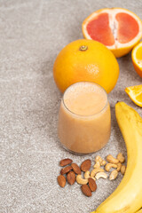 Fruit nut smoothie in a glass on a stone background.