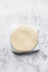 Overhead view of sugar cookie dough wrapped in parchment paper, process of making sugar cookies