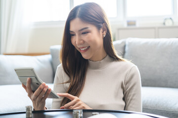 Saving money wealth concept, asian young business woman using calculator for calculate saving cost, cash finance planning to spend enough money on her income for save money, payment tax, investing.