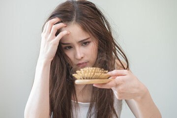 Damaged hair, amazed asian young woman, girl hand holding brush comb, hairbrush with fall hair from...