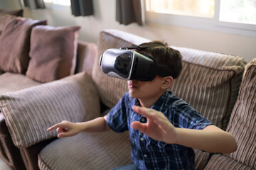 Young kid immerse within the Virtual reality world wearing VR headset gaming and entertainment having fun. At home living room relaxing on sofa online internet device technology concept.