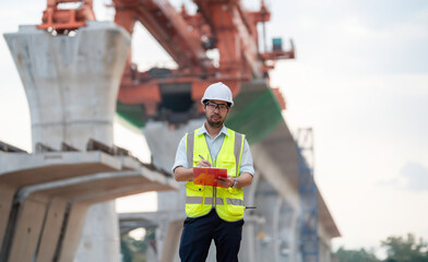 An Asian male engineer works at a motorway bridge construction site,Civil worker inspecting work on...