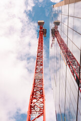 Red crane reflected on glass building 