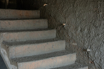 Newly made stairs of concrete during construction of new home with some pipes near stairs for led stair light connection.