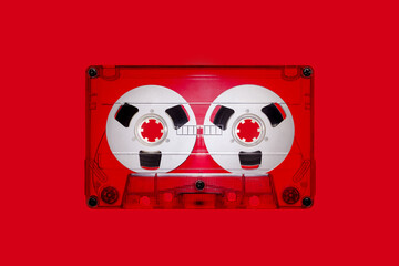 Clear plastic retro audio cassette with spools, isolated on red background in close up. The picture...