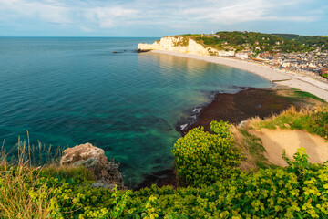 Panoramic view of pebble beach with white chalk cliffs and natural arches in Etretat town and...