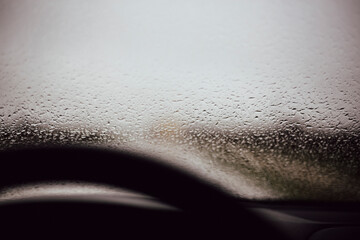 Raindrops blurring the view from an inside car cockpit view