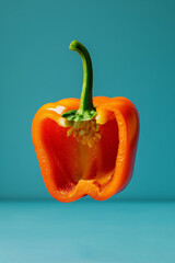 Orange bell pepper halves in perfect symmetry, with a single seed falling, on a tranquil blue backdrop - AI Generated