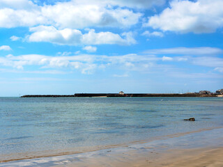 A view from the seafront towards the harbour at Lyme Regis with the sea reflecting bands of colour from the stormy sky