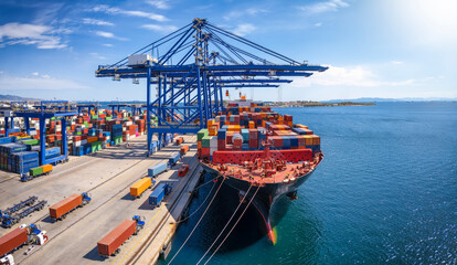 A large container cargo ship is beeing loaded and unloaded in a commercial dock - Powered by Adobe