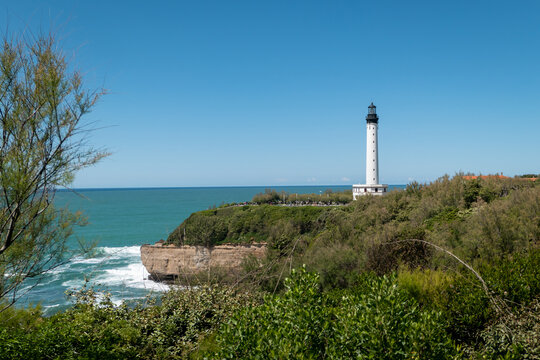 Entre alguns arbustos um farol no alto do desfiladeiro de frente para o mar em Biarritz na Fran&ccedil;a