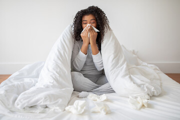 Young Woman Sitting in Bed Blowing Nose Suffering From Cold