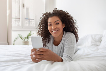 Woman Laying on Bed Holding Cell Phone