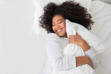 Woman Laying in Bed With White Blanket, Hugging Pillow
