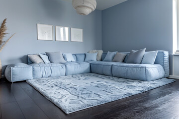 A serene, sky blue living room that feels like a breath of fresh air. A large, light grey rug on dark hardwood floors complements the sky blue walls. 