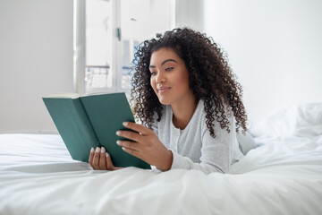 Woman Laying on Bed Reading a Book