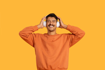 Man in Orange Shirt Listening to Headphones