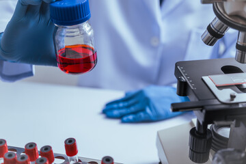 Hands of a doctor or female doctor collecting blood sample tubes from rack with analyzer in lab....