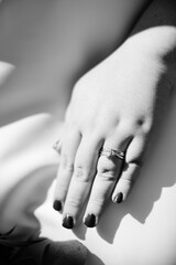 A black and white close-up of a bride's hand with a engagement ring. 