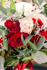 A close-up of a beautiful flower arrangement with green leaves, pink, and red roses. 