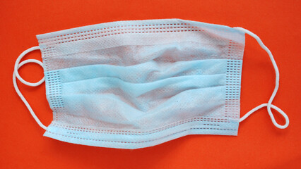 Blue medical single-pink mask on a red background, top view.