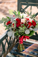 A gorgeous classic rose bouquet with greenery on a bench 