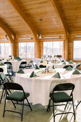 Fototapeta na wymiar A simple wedding reception at a lodge with hold up chairs and white tablecloth table.