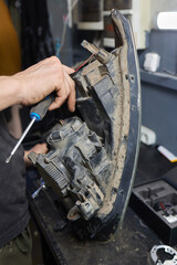 Person fixing Automotive lighting with screwdriver on Motor vehicle headlight