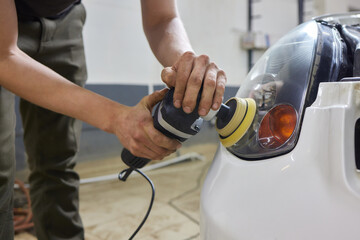Person using a machine to polish automotive lighting on a car headlight