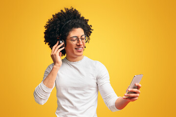 Cheerful young african man in headphones using music mobile application