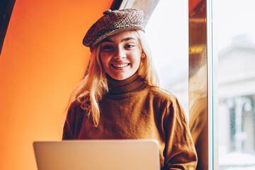 Portrait of cheerful female freelancer satisfied with successful online business working on free...
