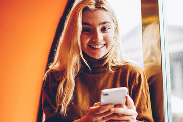 Portrait of cheerful hipster girl celebrating victory in online contest get email on smartphone,...