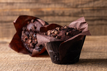 Chocolate dark muffin with chocolate chips and drops on a wooden table 